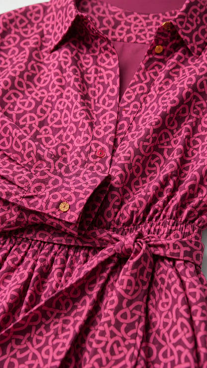 Close-up detail of collar, button placket, cuffs, and waist tie on magenta printed shirt dress