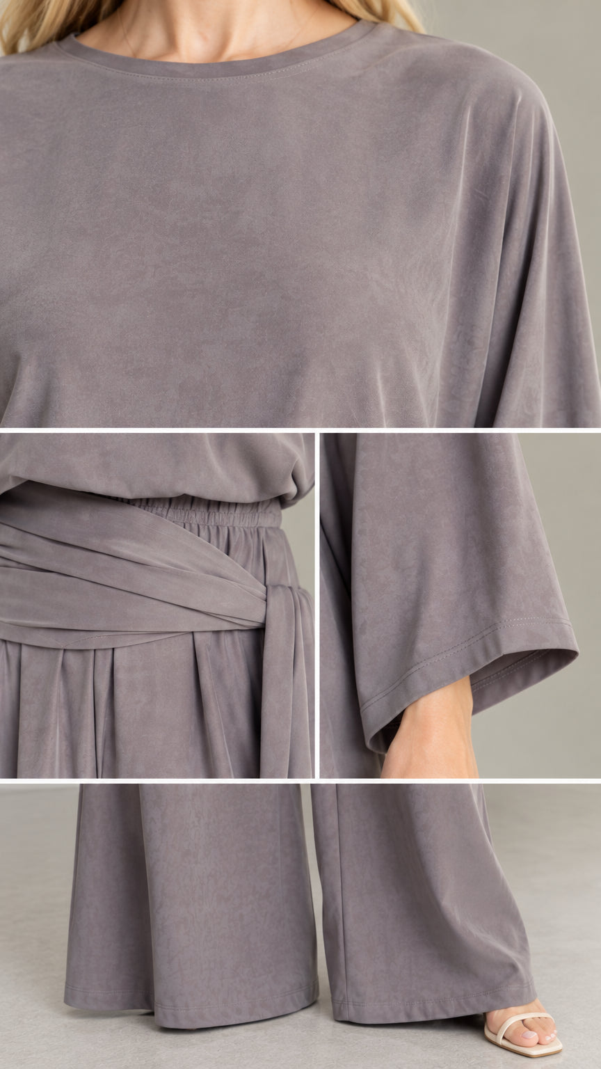 Close-up details of neckline, waist sash wrap, and fabric texture of slate grey jumpsuit