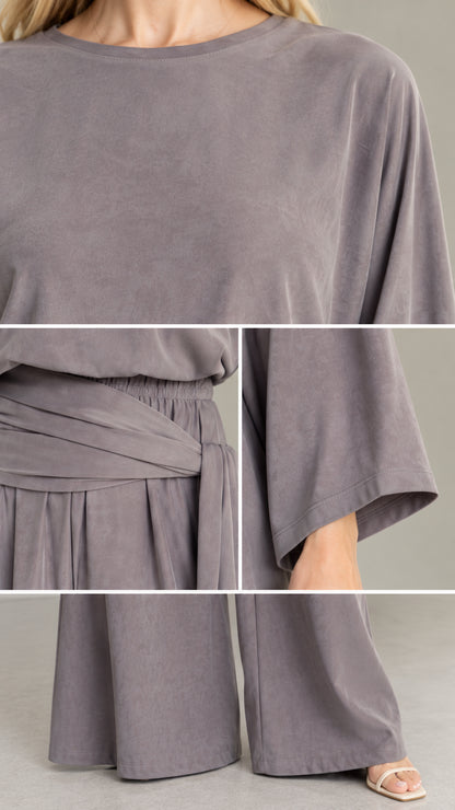 Close-up details of neckline, waist sash wrap, and fabric texture of slate grey jumpsuit