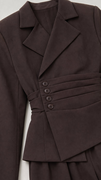 Close-up detail of chocolate brown asymmetric pleated blazer with covered buttons and lapel