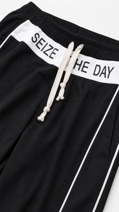 Close-up detail of black pant waistband with white Seize The Day lettering and drawstring