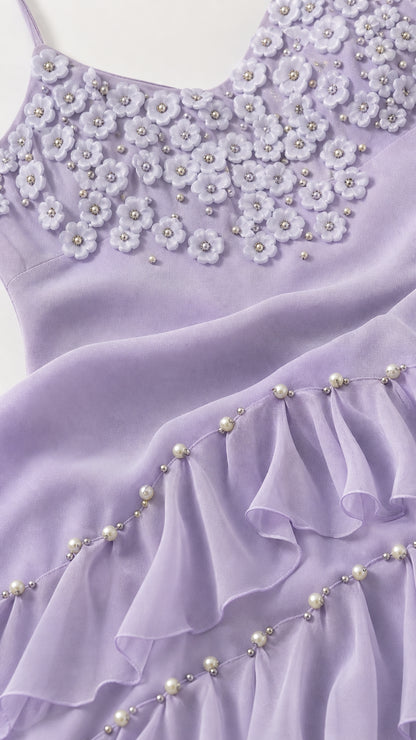 Close-up detail of 3D floral appliques and pearl-accented ruffled hemline