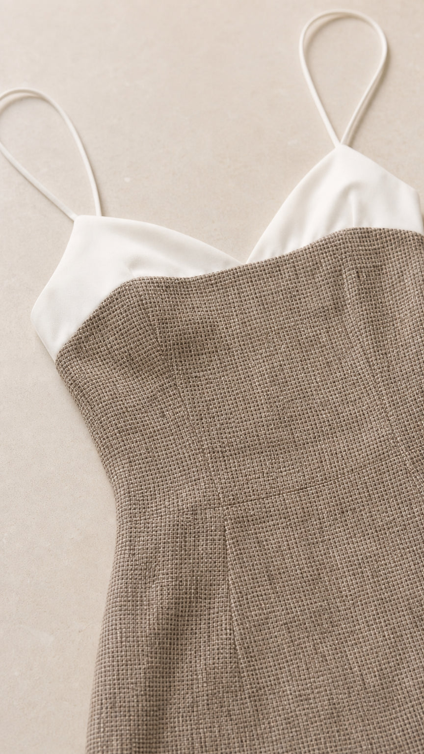 Close-up detail of white contrast sweetheart neckline and textured taupe fabric