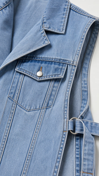 Close-up of lapel, chest pocket, and side buckle on light blue denim vest