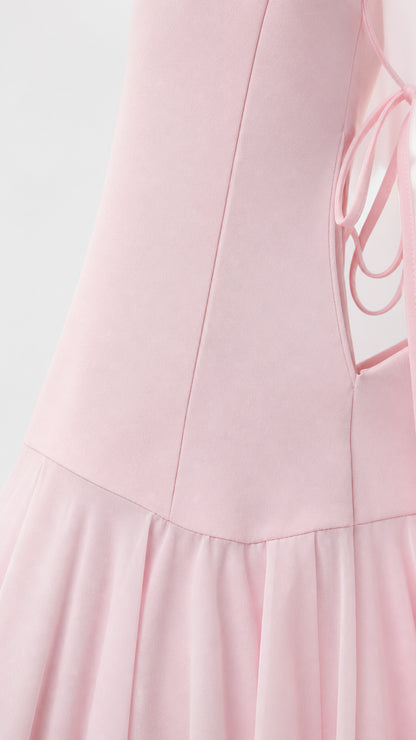 Close-up of pink dress side lace-up detail and pleated hem