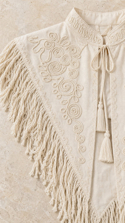 Close-up detail of intricate soutache scroll embroidery and tassel fringe on cream fabric
