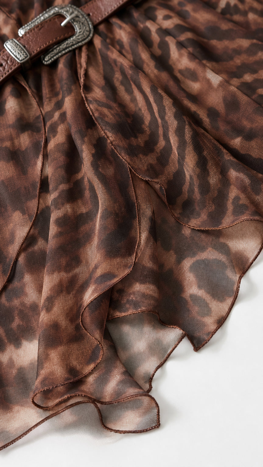 Close-up detail of sheer layered ruffle trim and buckled belt on brown maxi dress