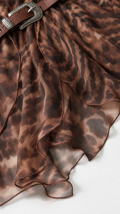 Close-up detail of sheer layered ruffle trim and buckled belt on brown maxi dress