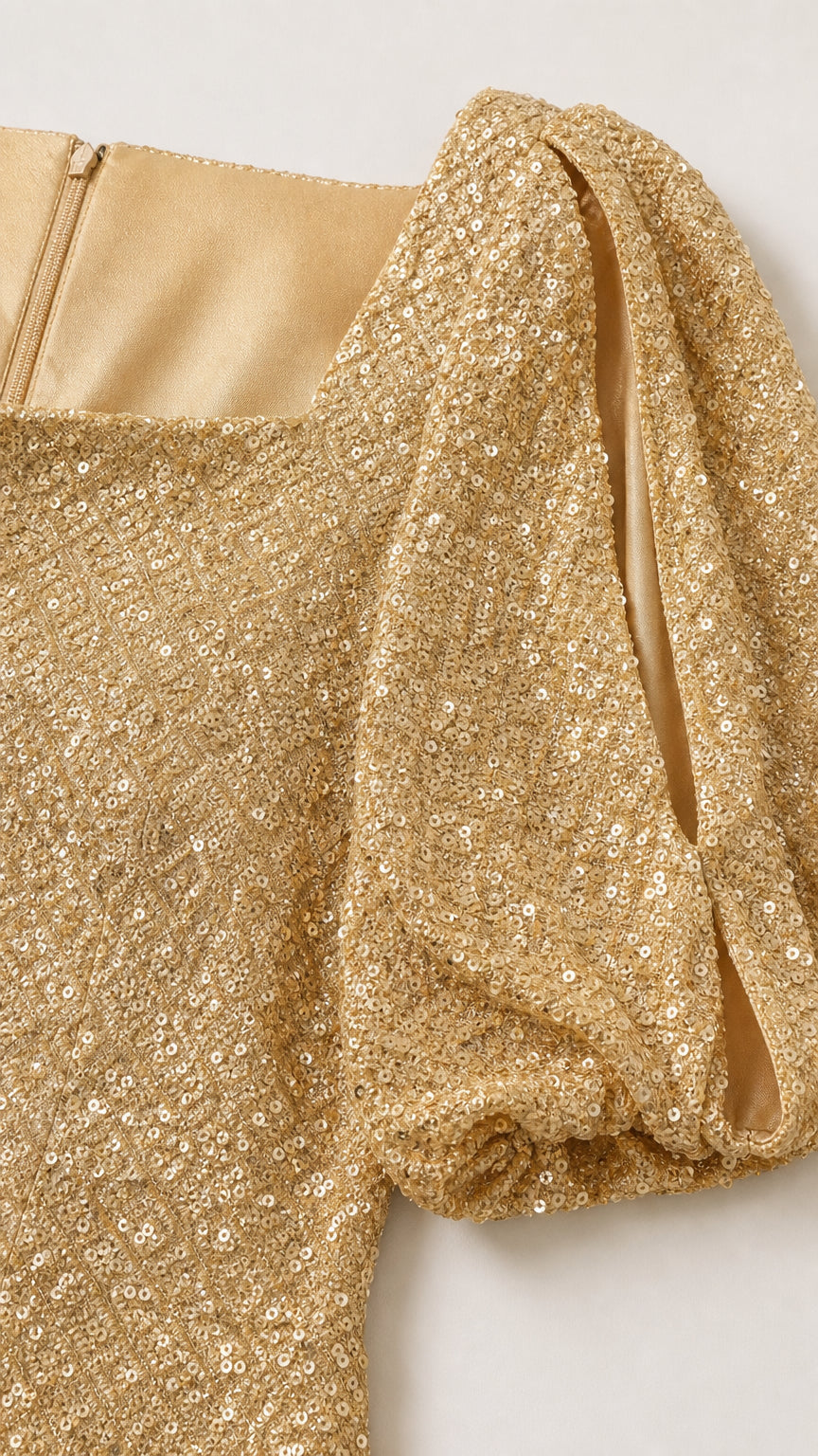 Close-up of the gold sequin fabric and puff sleeve detail