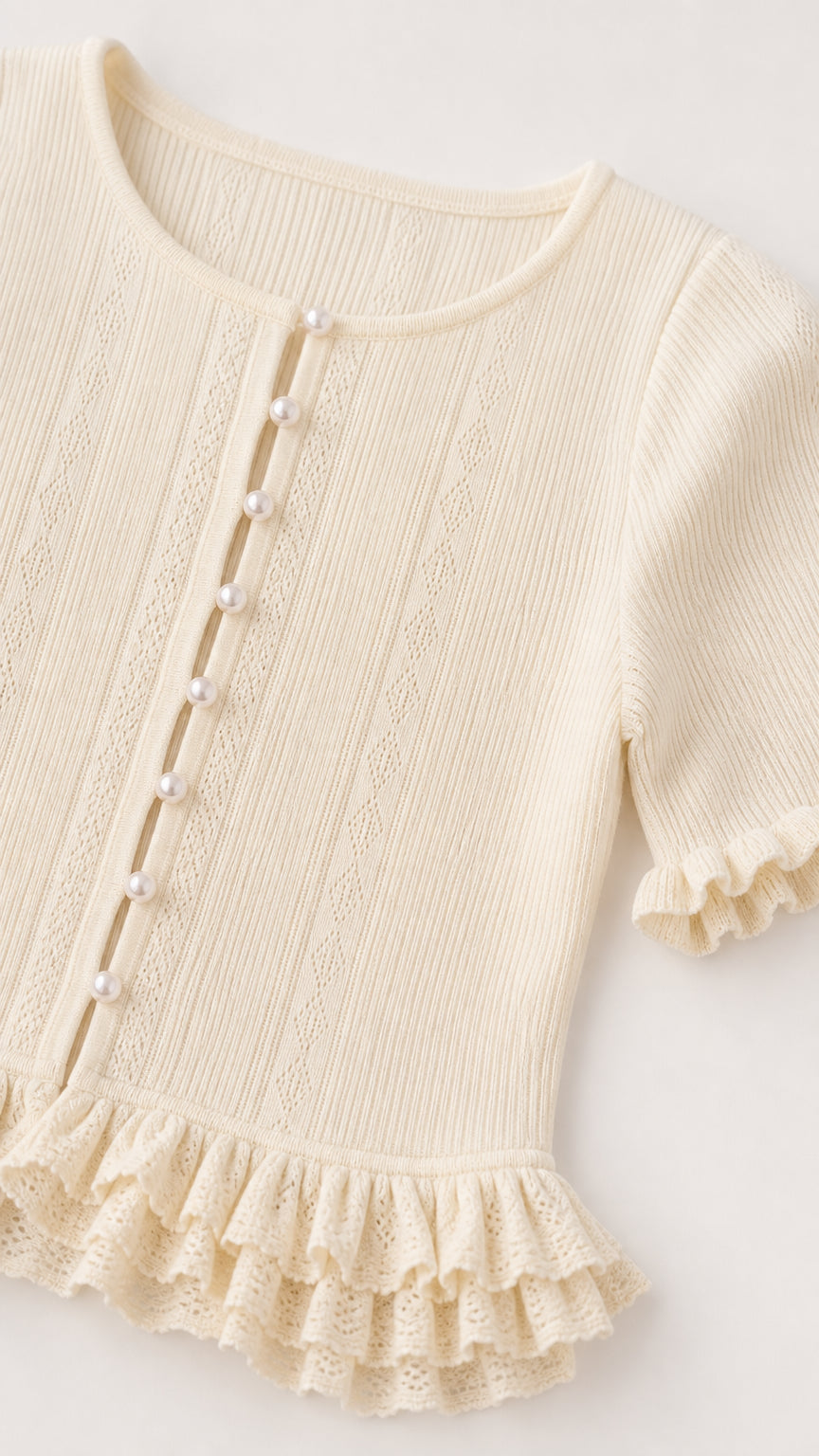 Close-up detail of off white ribbed knit top with pearl buttons and ruffled hem
