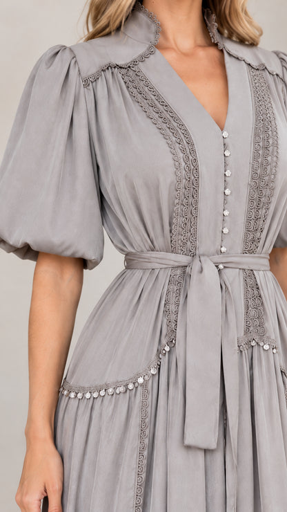 Close-up detail of lace trim, V-neckline, and puff sleeve on grey maxi dress