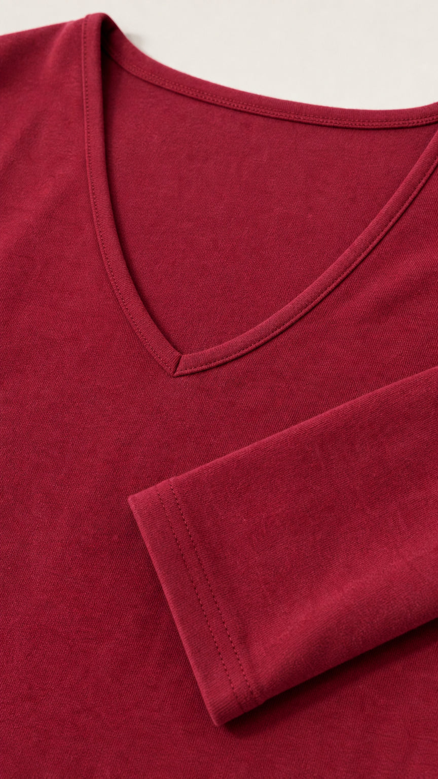Close-up detail of V-neckline and bell sleeve cuff on soft burgundy fabric