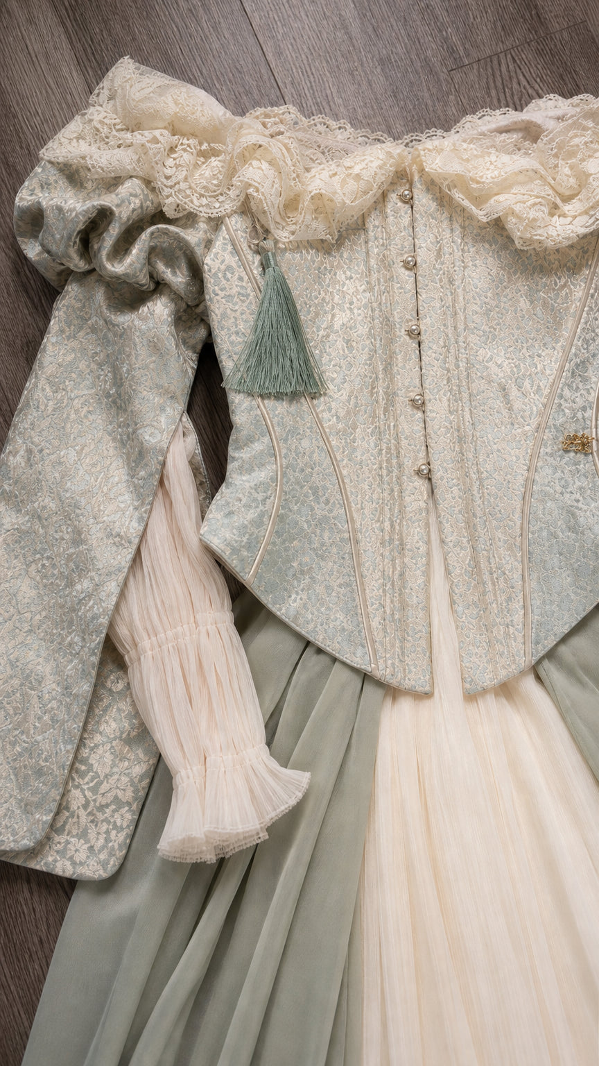 Close-up detail of the lace collar, sleeves, and patterned bodice of the sage green gown