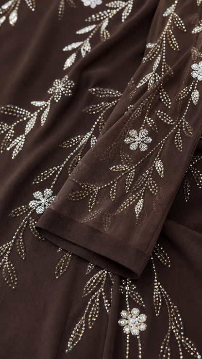 Close-up detail of shimmering floral and vine rhinestone embellishments on chiffon fabric
