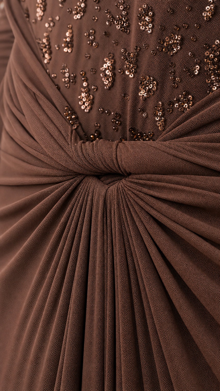 Close-up detail of the gathered twist-knot waist and scattered sequin embellishments on brown fabric