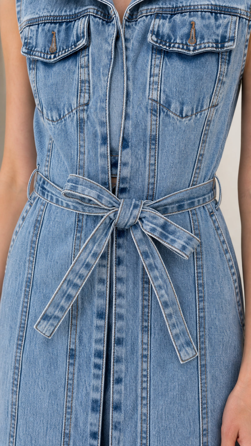 Close-up detail of chest pockets and waist tie on light blue denim dress