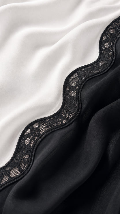 Close-up fabric detail showing white satin texture and black lace trim