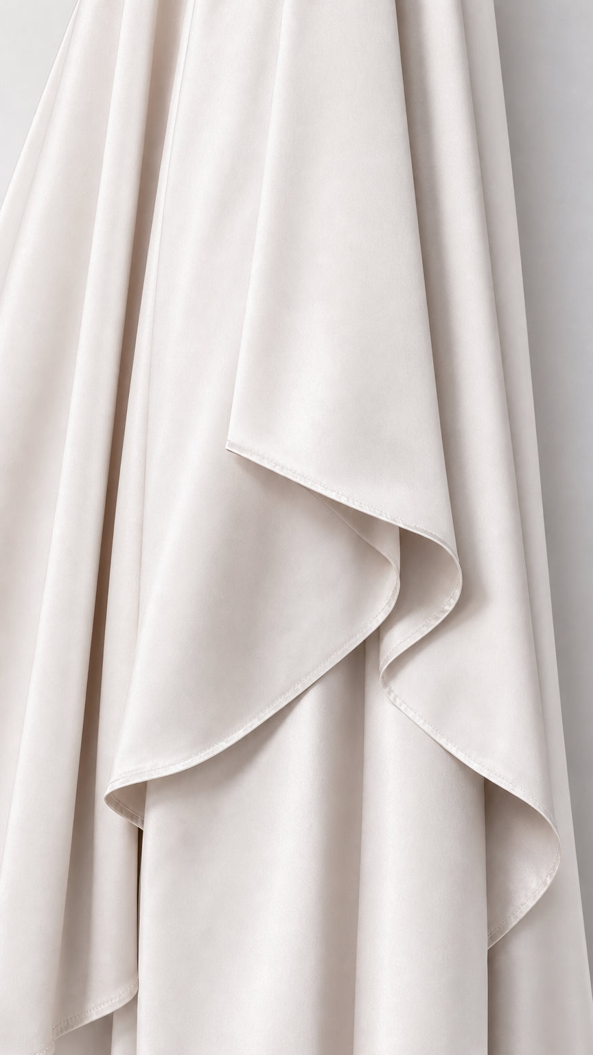 Close-up detail of Cream satin fabric with asymmetric draped hem