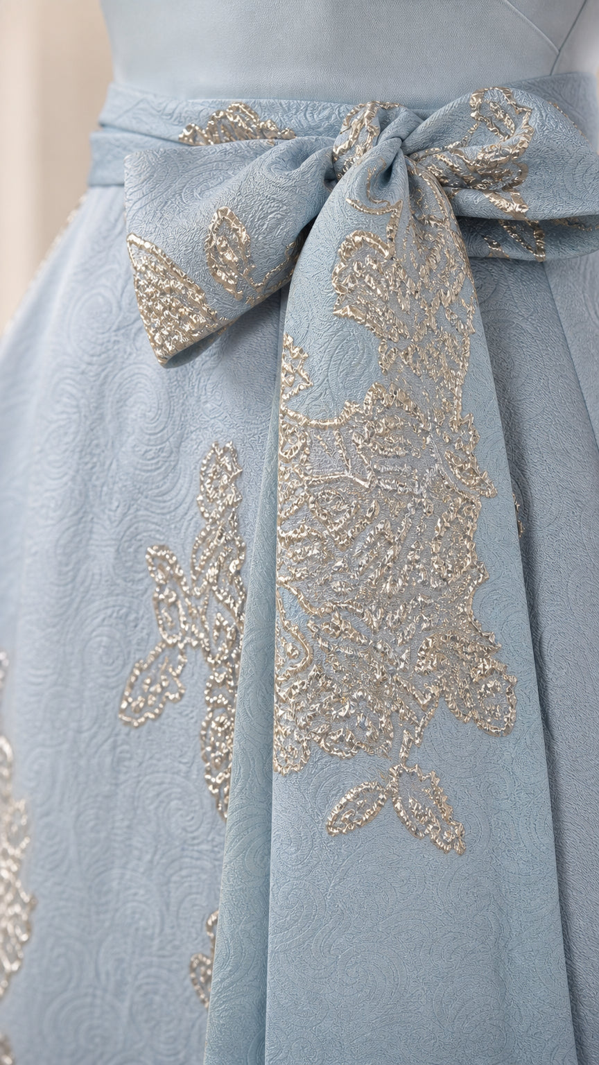 Close-up detail of the metallic floral jacquard fabric and waist tie
