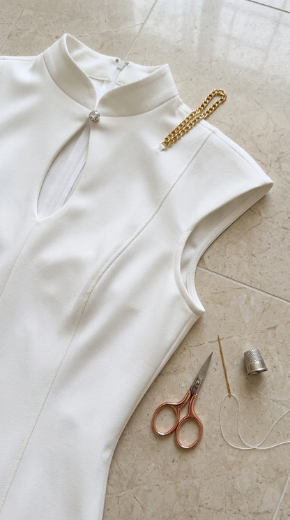 Close-up detail of high collar, keyhole neckline, and craftsmanship on white dress