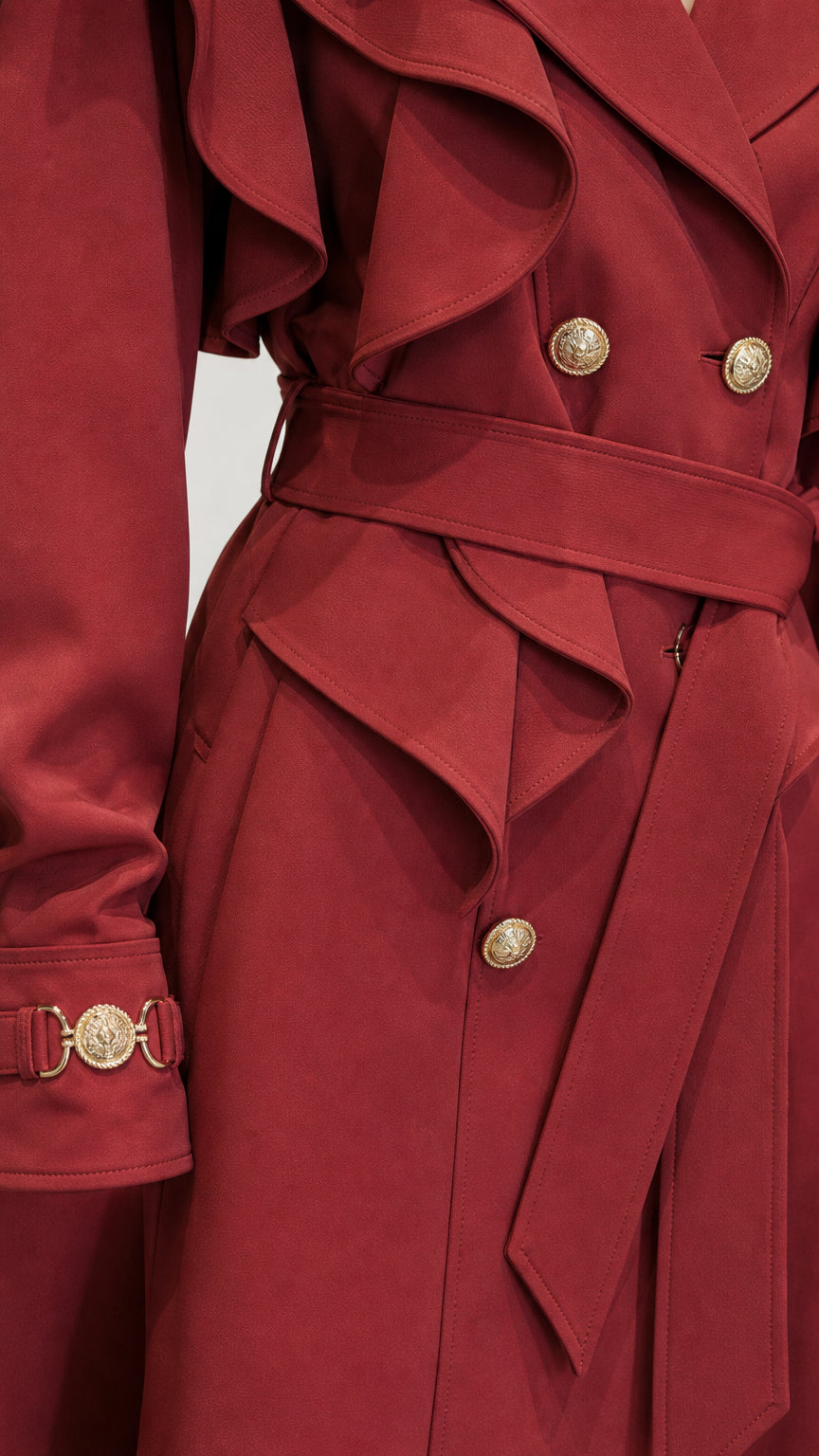 Close-up detail of ruffle capelet and gold buttons on red trench coat