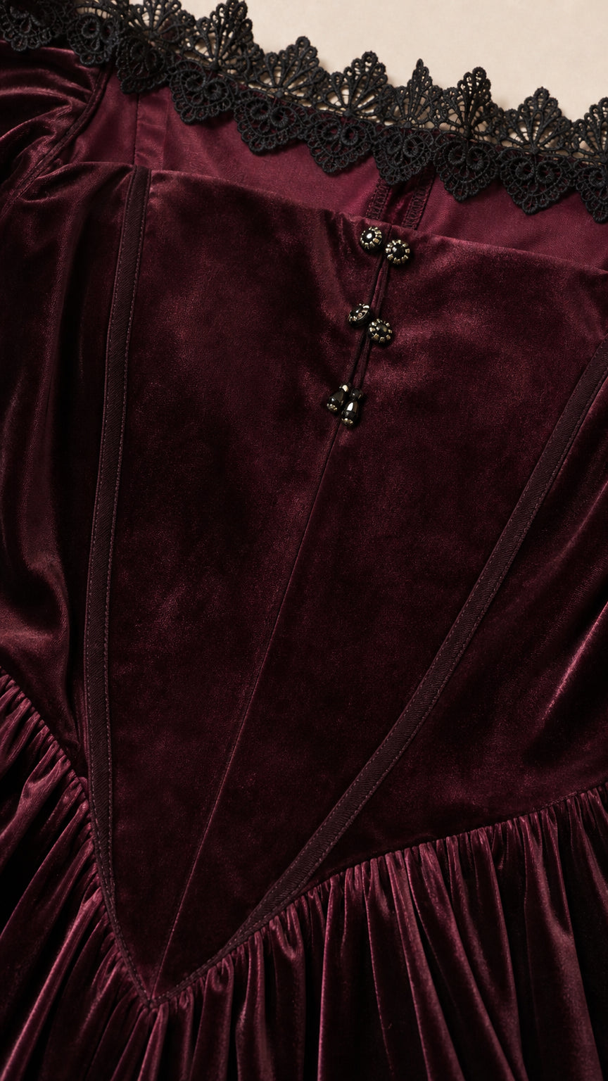 Close-up detail of black lace trim and buttons on Burgundy velvet dress