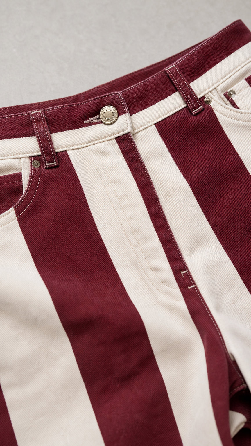 Close-up of waistband and button detail on striped trousers