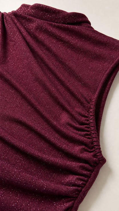 Close-up detail of textured burgundy fabric with metallic shimmer and shoulder ruching