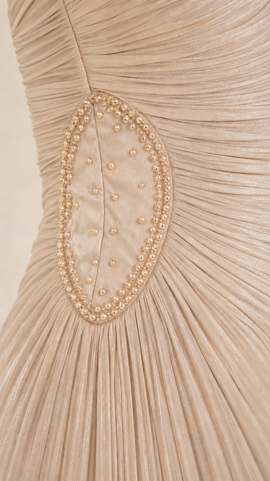 Close-up of beaded and pearl embroidered oval waist detail on champagne pleated dress