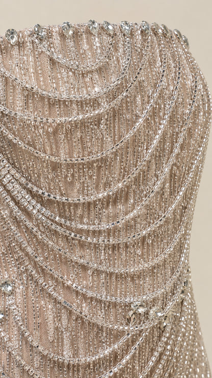 Close-up detail of shimmering beadwork and draped chains on dress bodice