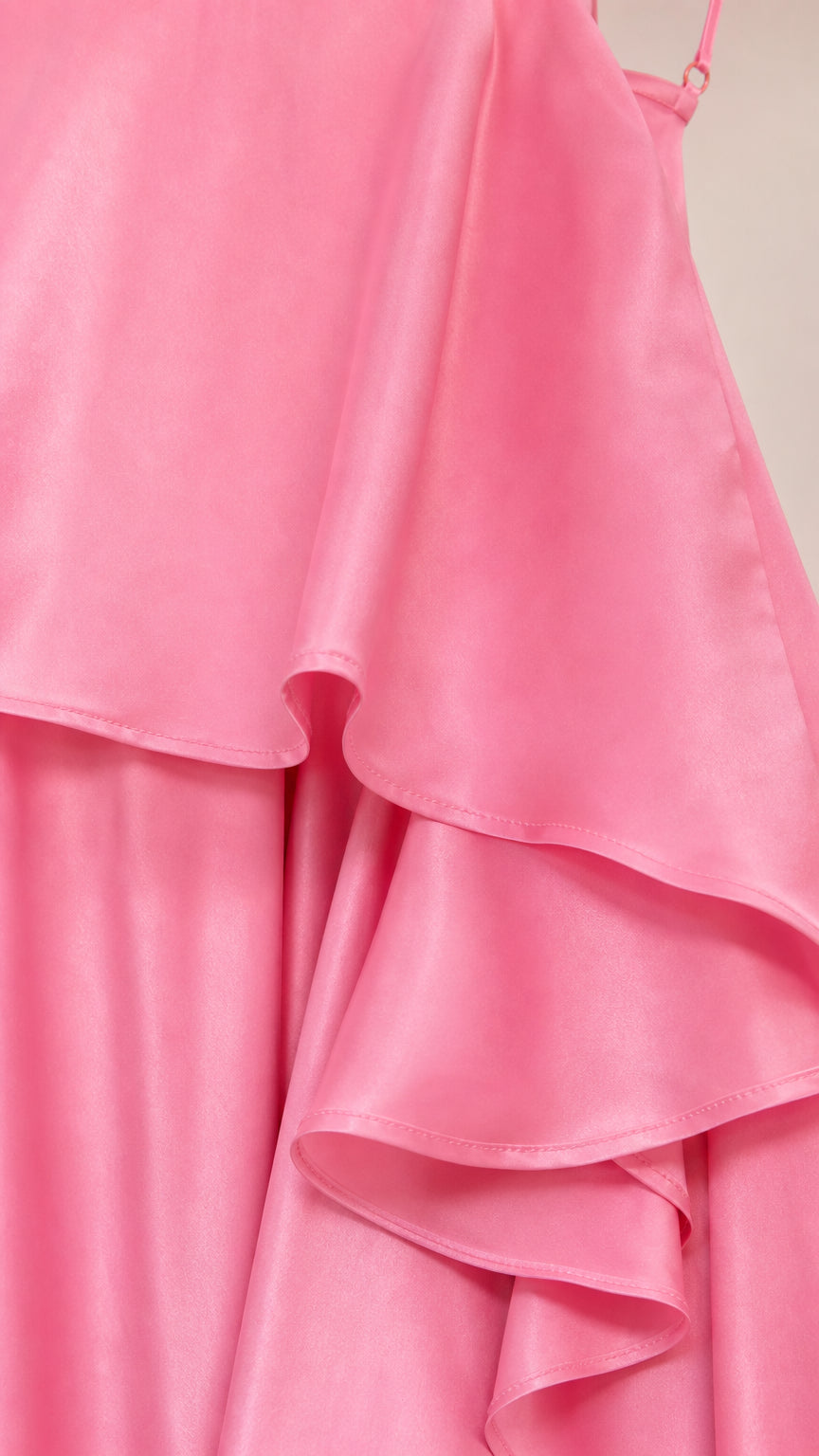 Close-up detail of smooth pink satin fabric and ruffle layers