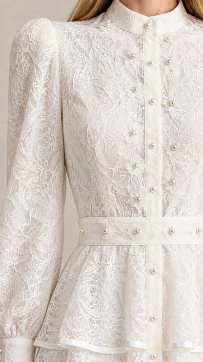 Close-up detail of bodice showing floral lace pattern, pearl buttons, and embellished waistband