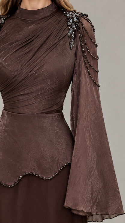 Close-up of ruched neckline, beaded shoulder detail, and textured bell sleeves on brown gown