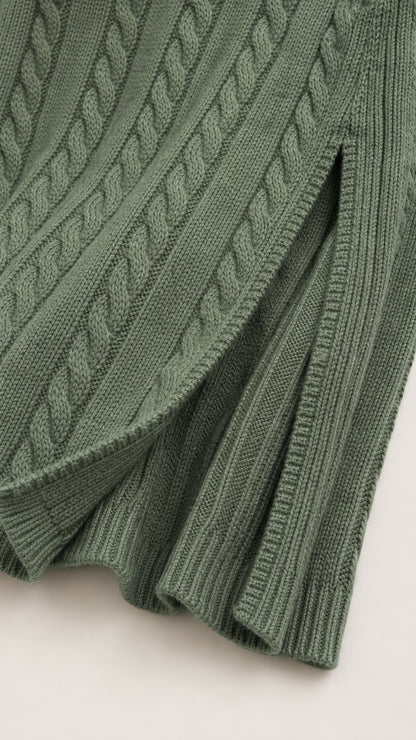 Close-up detail of green cable knit texture, ribbed hem, and front slit