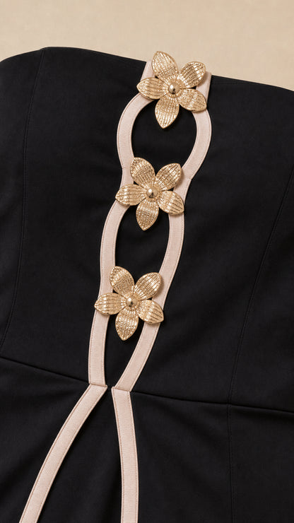 Close-up of gold floral hardware and contrast trim on black jumpsuit