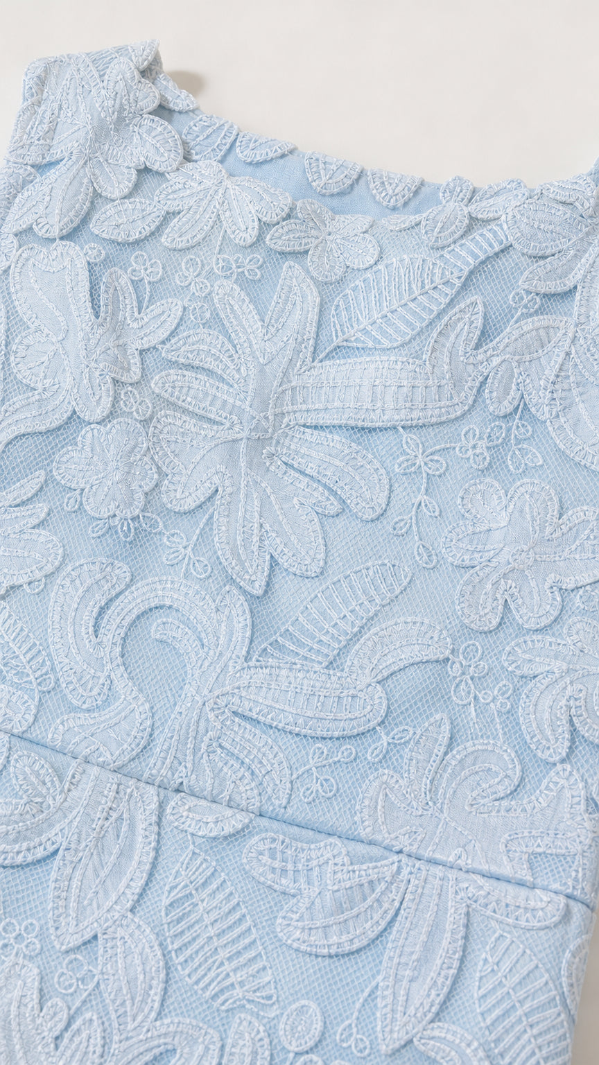 Close-up detail of embroidered floral lace fabric texture in light blue