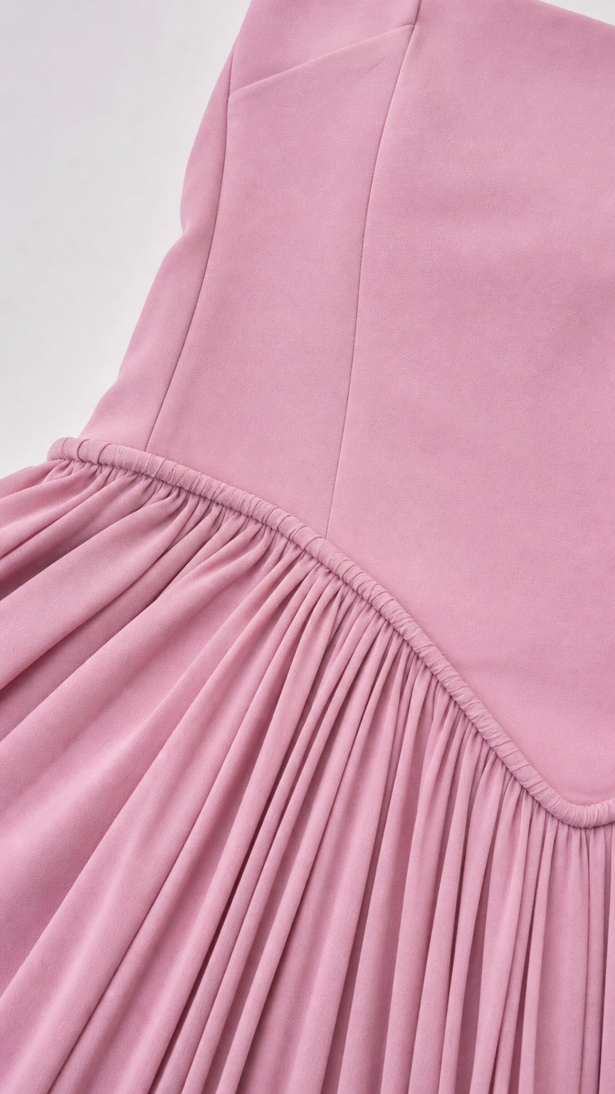 Close up detail of dusty pink drop waist seam and fine accordion pleating