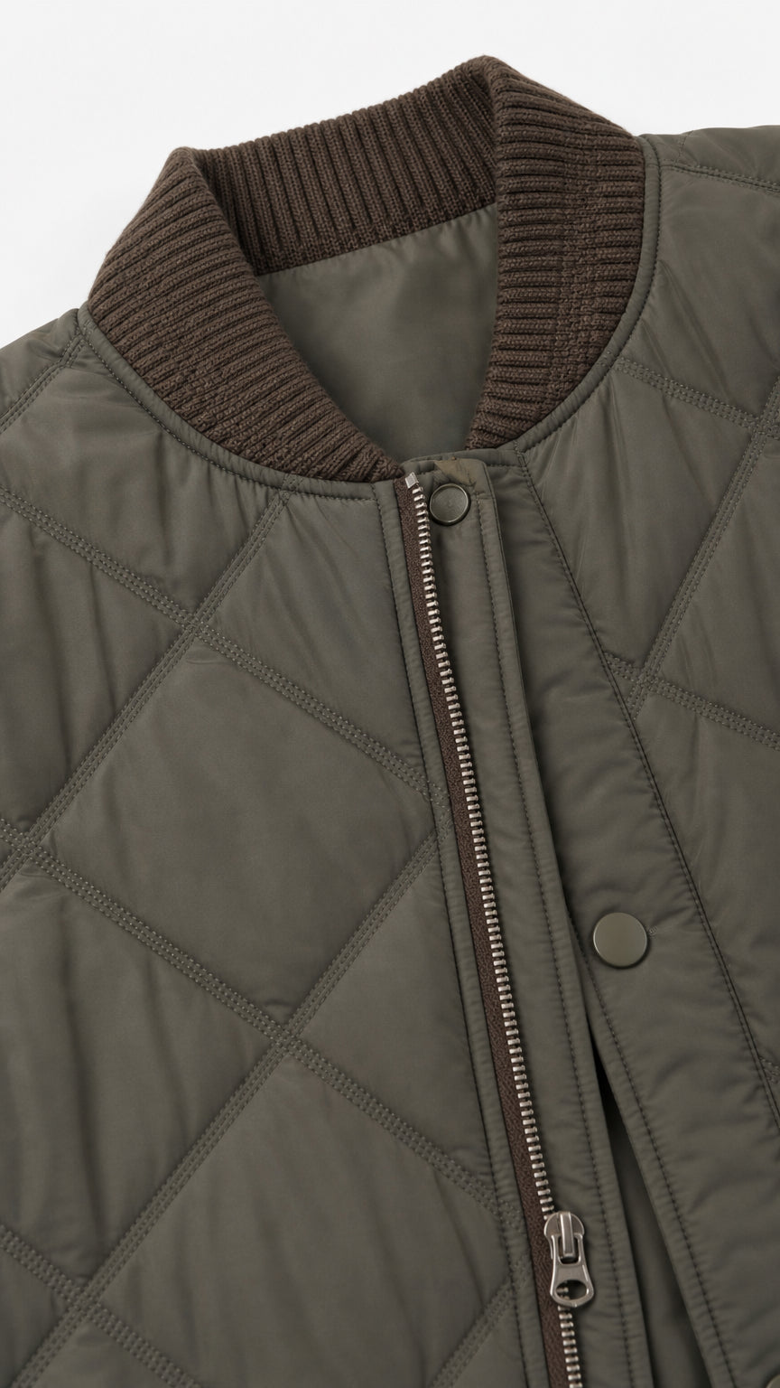 Close-up detail of olive green quilted fabric, ribbed neckline, and metal zipper