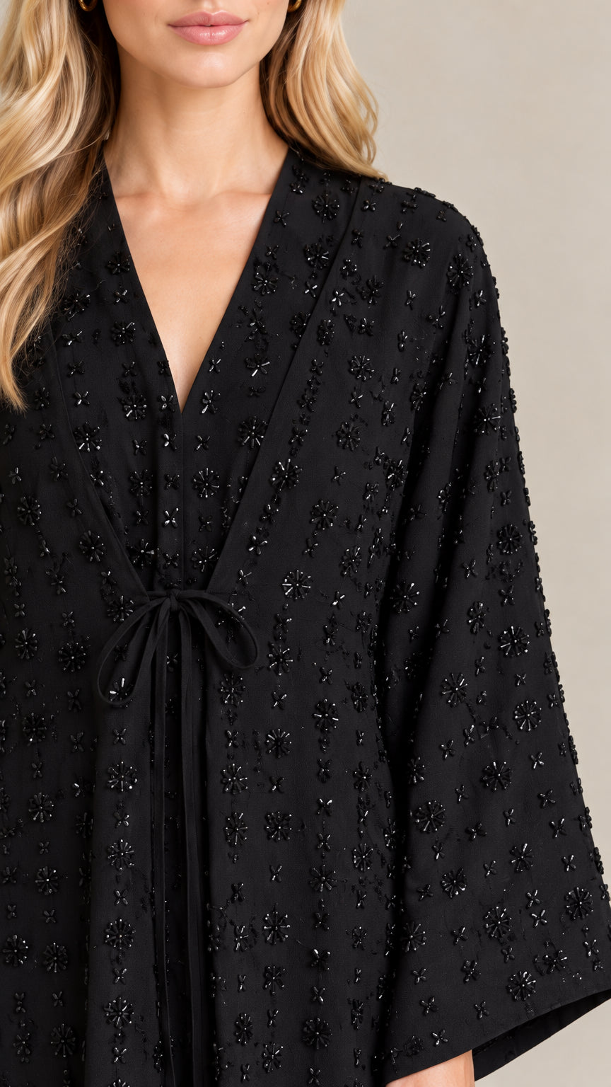 Close-up detail of V-neckline, tie waist, and intricate beadwork on Black abaya
