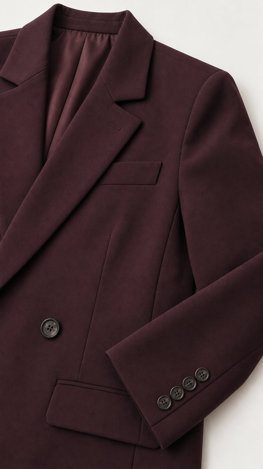 Close-up detail of burgundy suit lapel, chest pocket, and cuff buttons