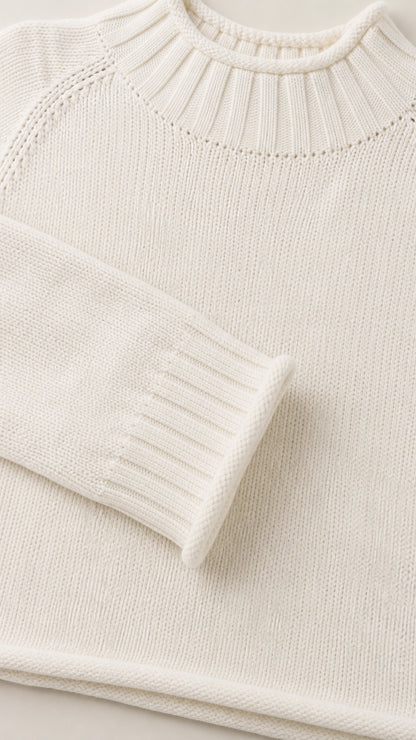 Close-up detail of white knit sweater collar and ribbed sleeve cuff
