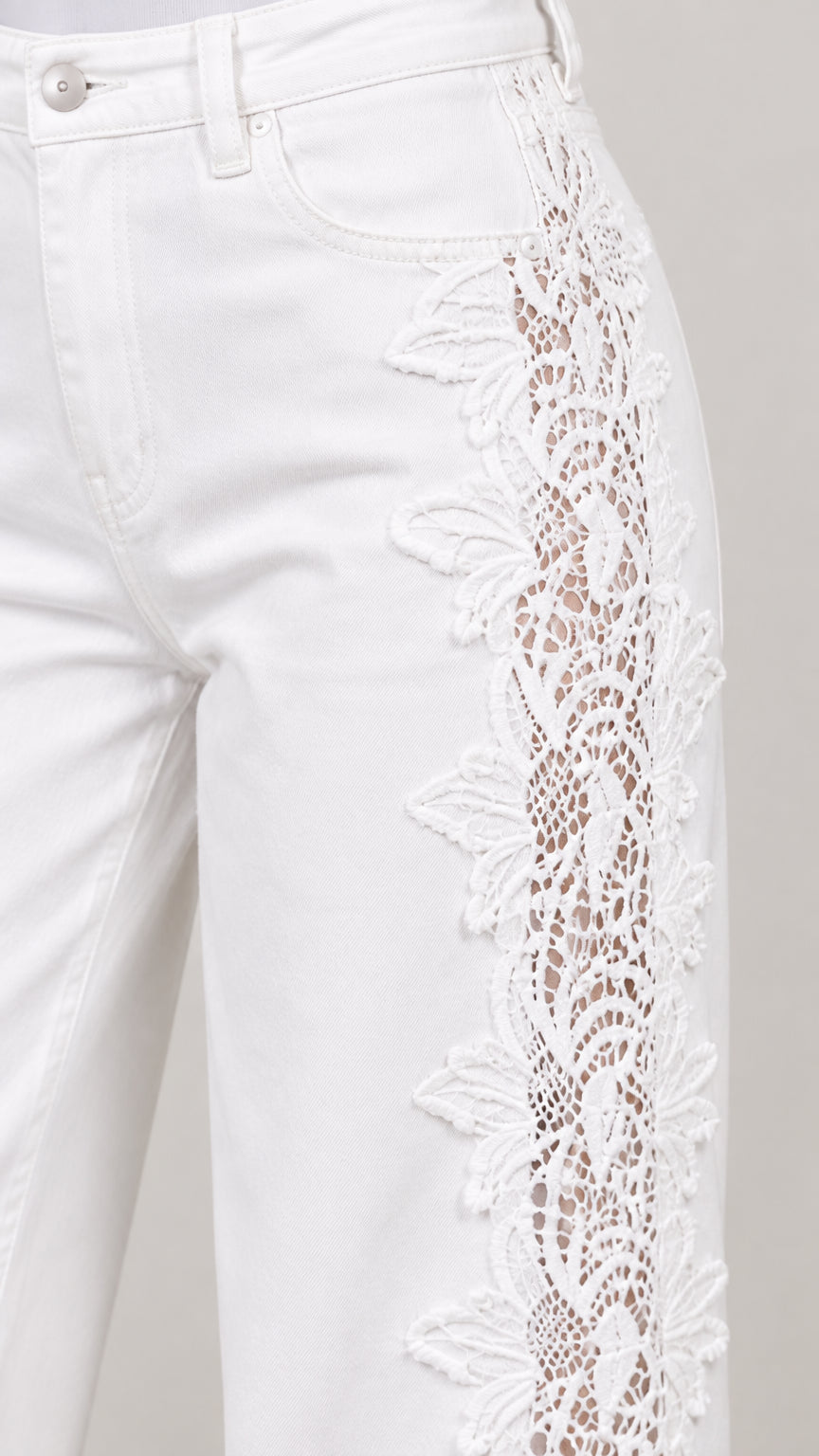 Close-up detail of white denim pocket and intricate floral lace side crochet insert