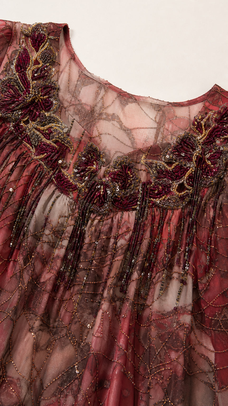 Close-up detail of beaded floral embellishments on neckline and pleated sheer fabric