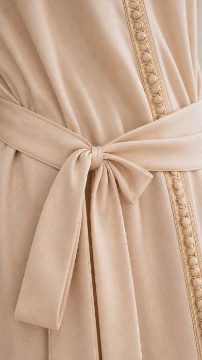 Close-up detail of waist tie belt and front beaded trim on beige fabric
