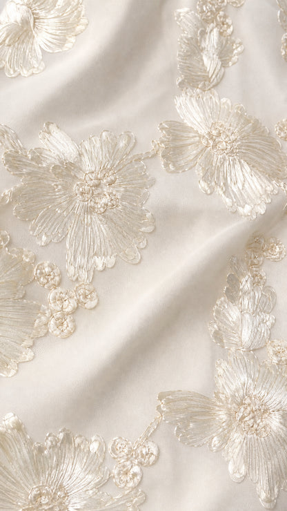 Close-up detail of white floral embroidery on fabric