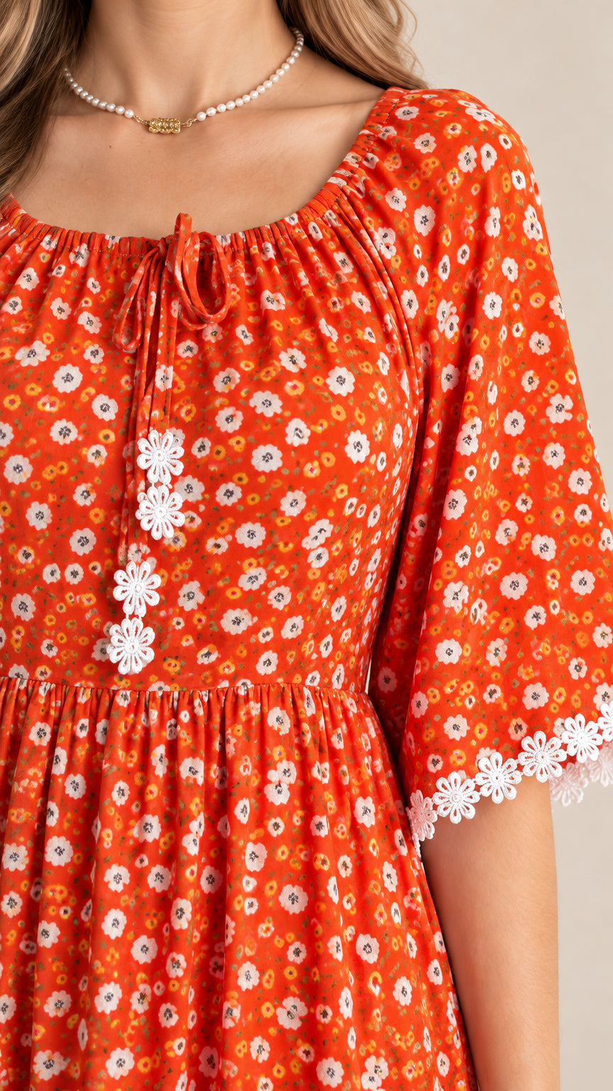 Close-up detail of neckline tie, floral print, and lace accents on rust orange dress
