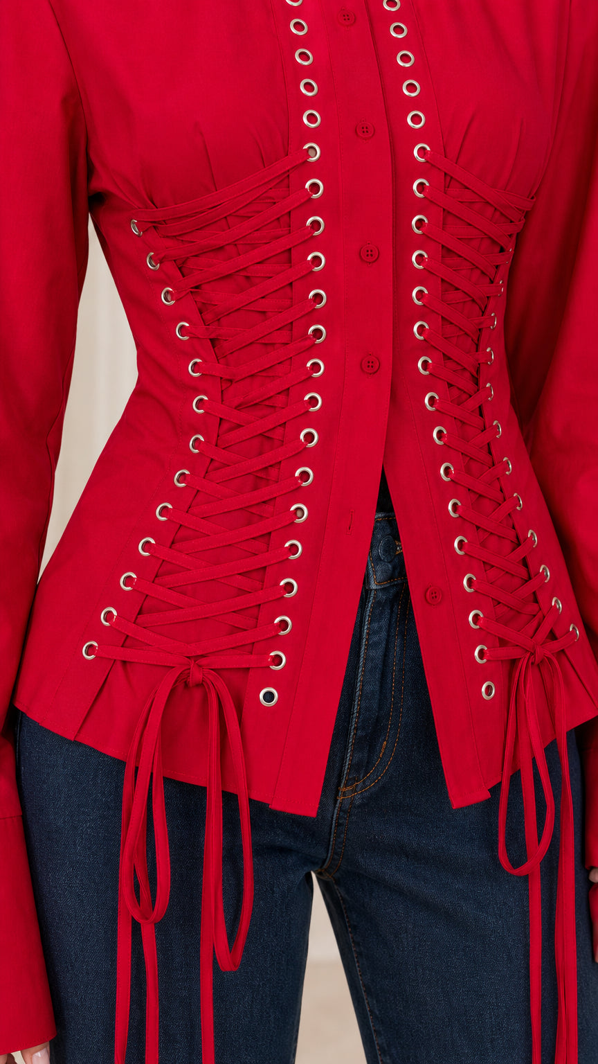 Close-up detail of front metal grommets and lace-up corset ties on red blouse