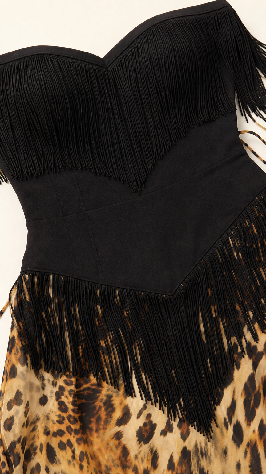 Close-up detail of sweetheart neckline, black fringe trim, and leopard skirt waist