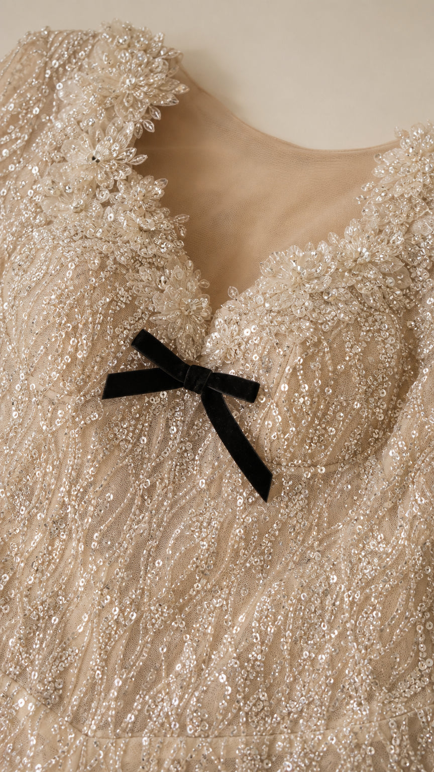 Close-up detail of scalloped sweetheart neckline with delicate black bow and sequin embroidery