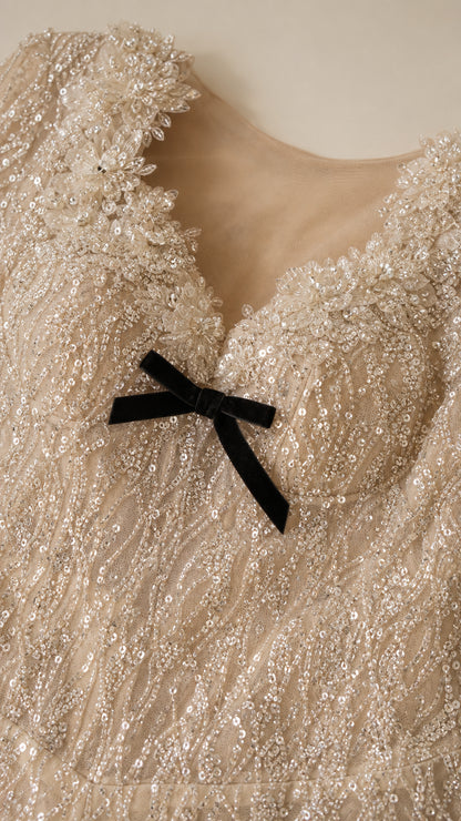 Close-up detail of scalloped sweetheart neckline with delicate black bow and sequin embroidery